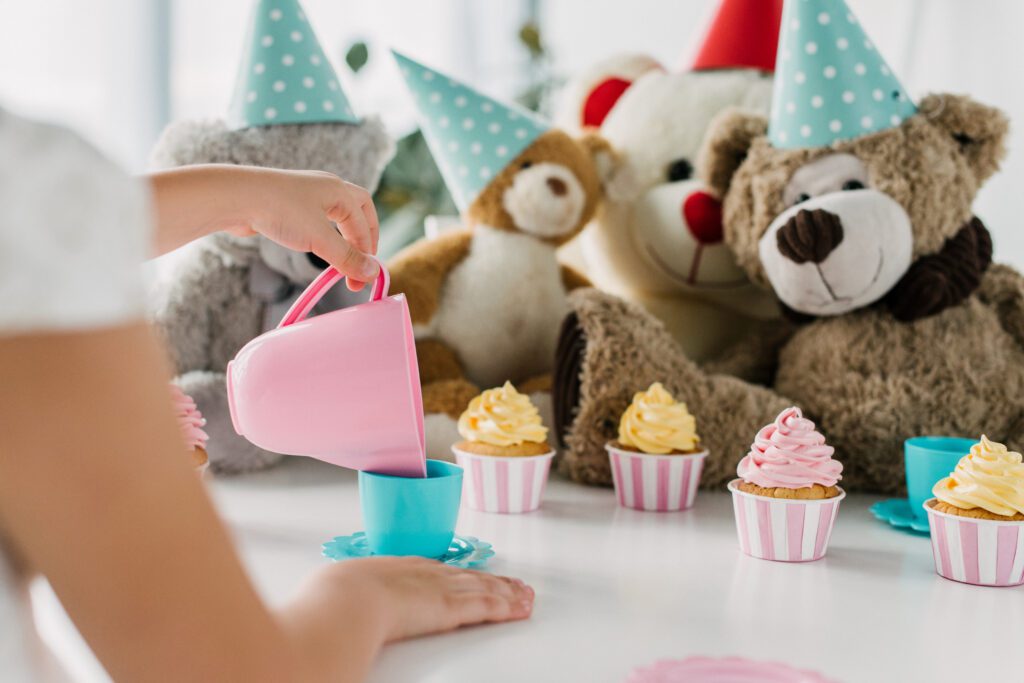 Cropped Image Of Kid Pouring Tea Into Cup To Teddy